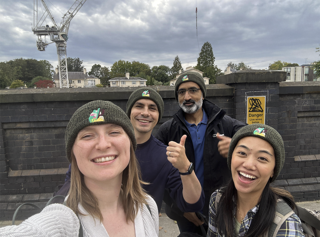 Four Trailmix teammates in matching Values beanies regrouping mid-checkpoint, laughing together for a selfie.