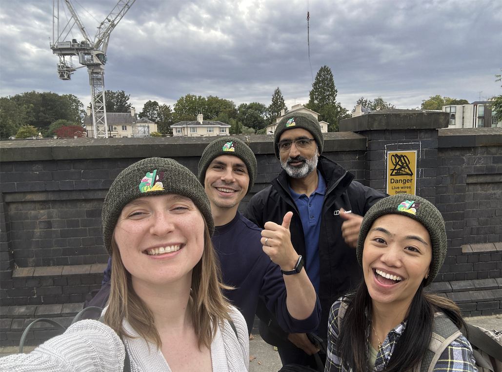 Four Trailmix teammates in matching Values beanies regrouping mid-checkpoint, laughing together for a selfie.